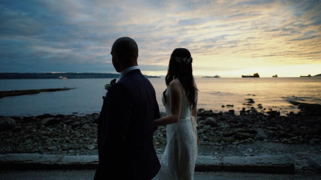 Bride and groom walking the beach at sunset in Stanley Park, Vancouver